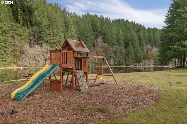 view of playground featuring a water view, a forest view, and a yard