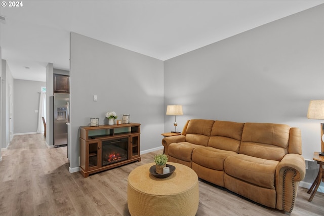 living room with light wood-type flooring, a glass covered fireplace, and baseboards