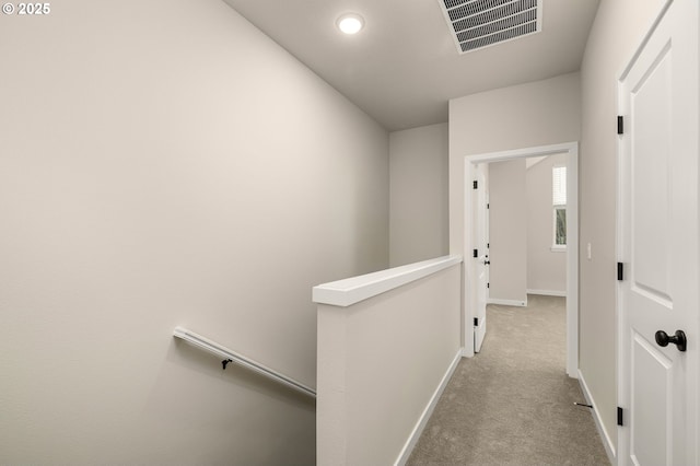 hall featuring an upstairs landing, visible vents, carpet floors, and baseboards