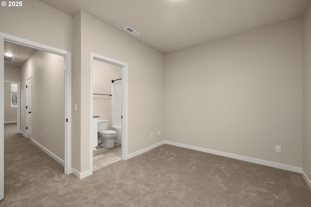 unfurnished bedroom with baseboards, visible vents, carpet floors, and connected bathroom