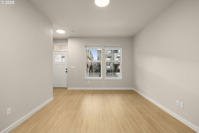 spare room with baseboards and light wood-style floors