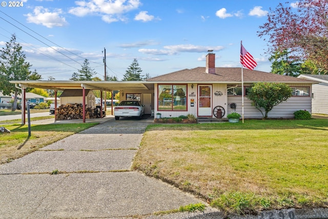 view of front facade with concrete driveway, a front yard, a shingled roof, an attached carport, and a chimney