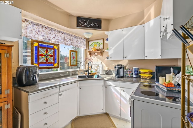 kitchen featuring sink, electric range, and white cabinets