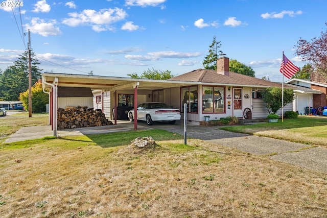 ranch-style home featuring aphalt driveway, an attached carport, a chimney, and a front yard