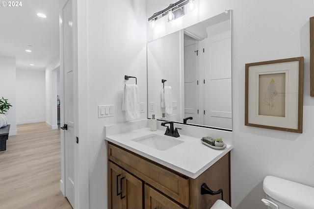 bathroom with hardwood / wood-style flooring, vanity, and toilet