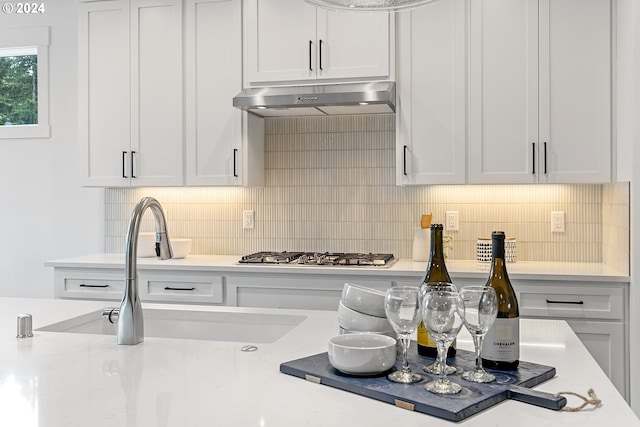 kitchen with white cabinets, stainless steel gas stovetop, sink, and backsplash