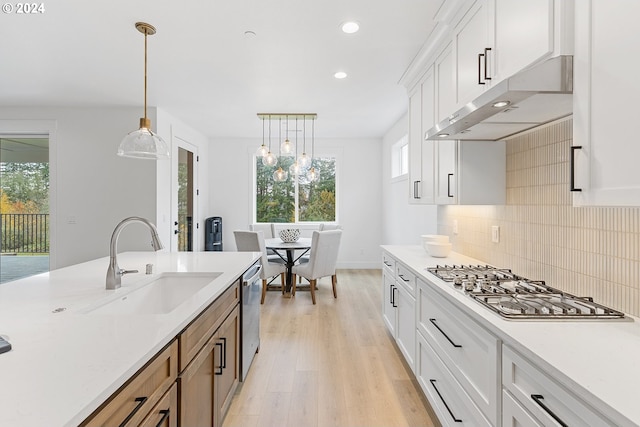 kitchen with white cabinetry, a wealth of natural light, sink, and pendant lighting