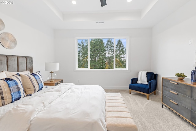 bedroom featuring a tray ceiling, light carpet, and ceiling fan