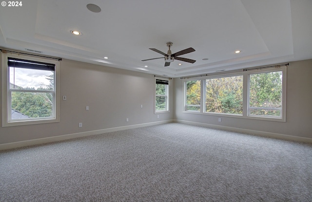 carpeted empty room with a tray ceiling and ceiling fan