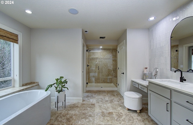 bathroom with vanity, shower with separate bathtub, and a textured ceiling