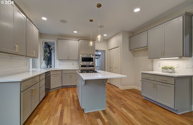 kitchen featuring appliances with stainless steel finishes, gray cabinetry, pendant lighting, light hardwood / wood-style floors, and a kitchen island