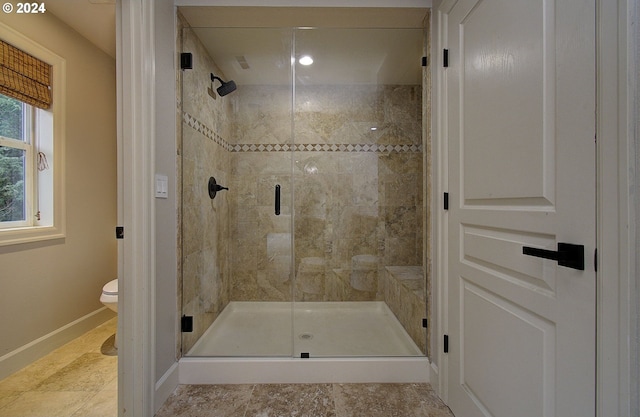 bathroom featuring toilet and a shower with door