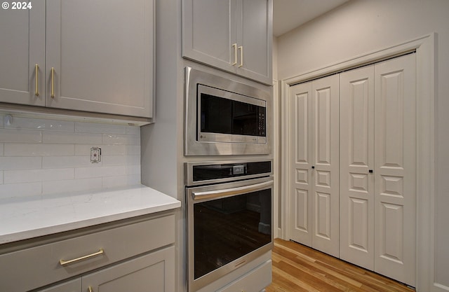 kitchen featuring tasteful backsplash, gray cabinetry, stainless steel appliances, and light wood-type flooring