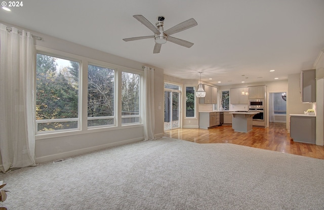 unfurnished living room with light hardwood / wood-style flooring and ceiling fan