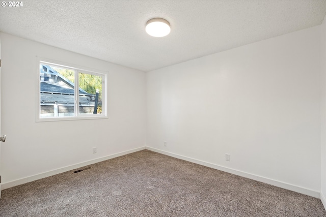 carpeted empty room featuring a textured ceiling