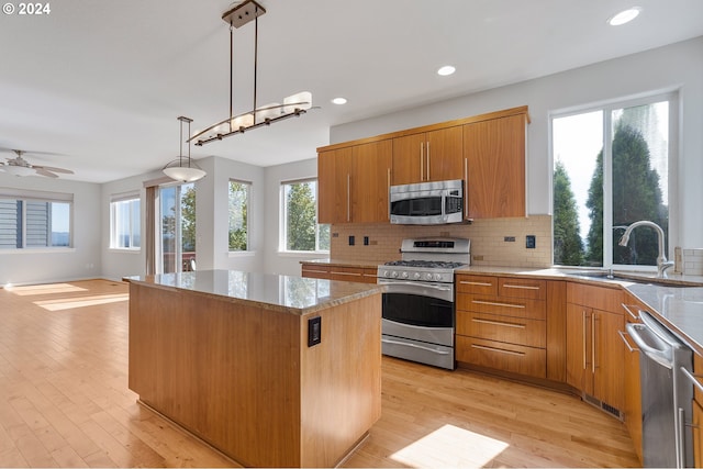 kitchen with a center island, appliances with stainless steel finishes, hanging light fixtures, and light hardwood / wood-style floors