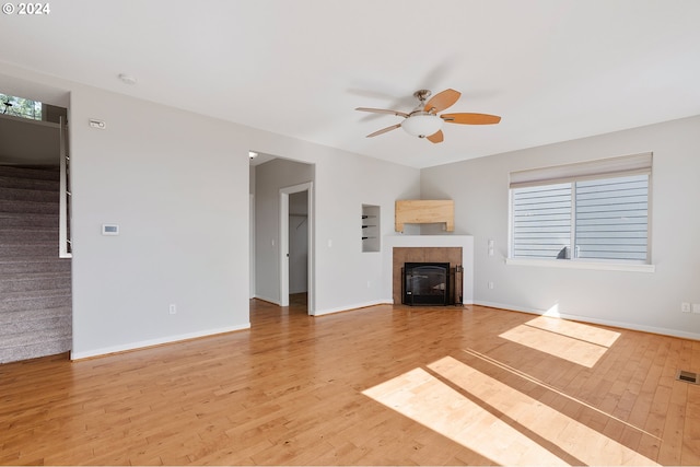 unfurnished living room featuring ceiling fan, a healthy amount of sunlight, light hardwood / wood-style flooring, and a fireplace