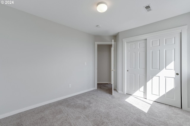 unfurnished bedroom featuring light carpet and a closet