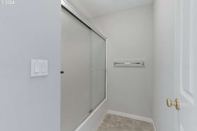 bathroom featuring combined bath / shower with glass door