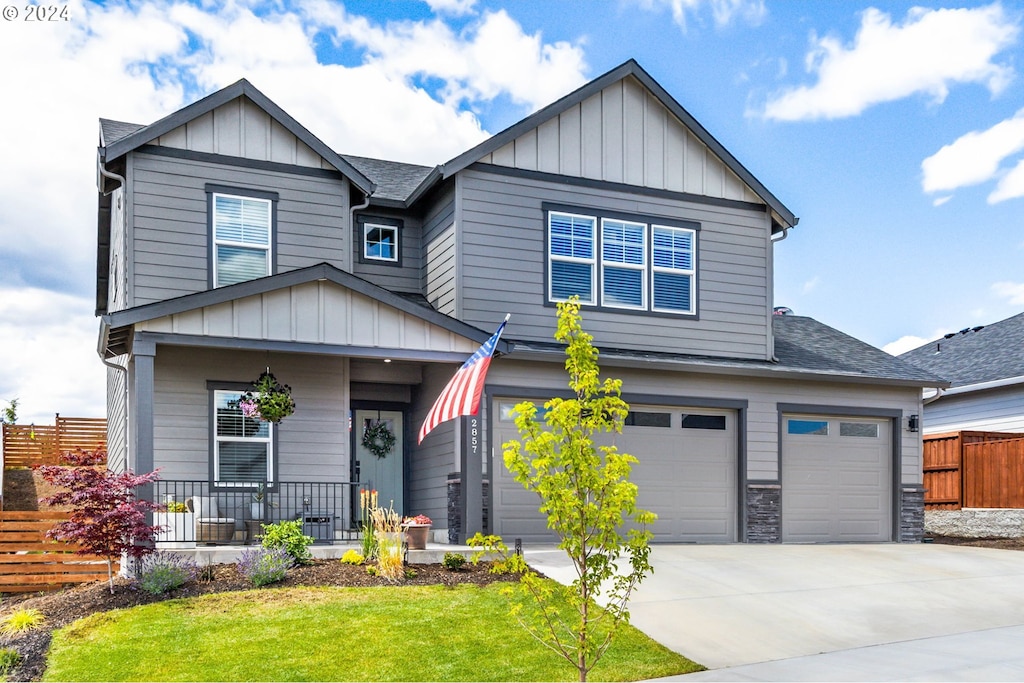 craftsman house with covered porch, a garage, and a front lawn