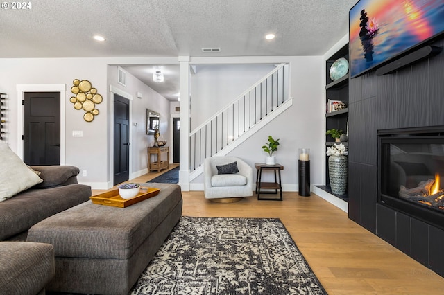 living room featuring built in shelves, a textured ceiling, and hardwood / wood-style flooring