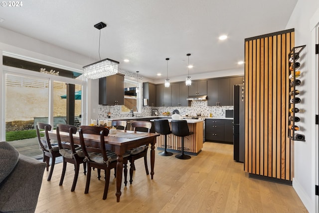 dining area with sink, light hardwood / wood-style flooring, and an inviting chandelier