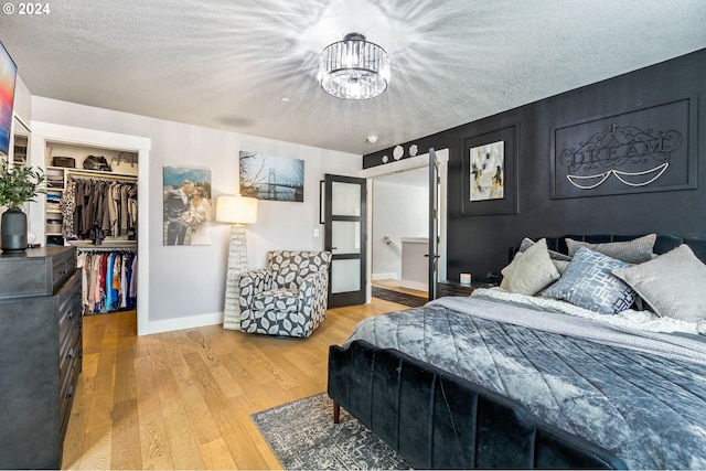 bedroom featuring hardwood / wood-style floors, a textured ceiling, a spacious closet, and a closet