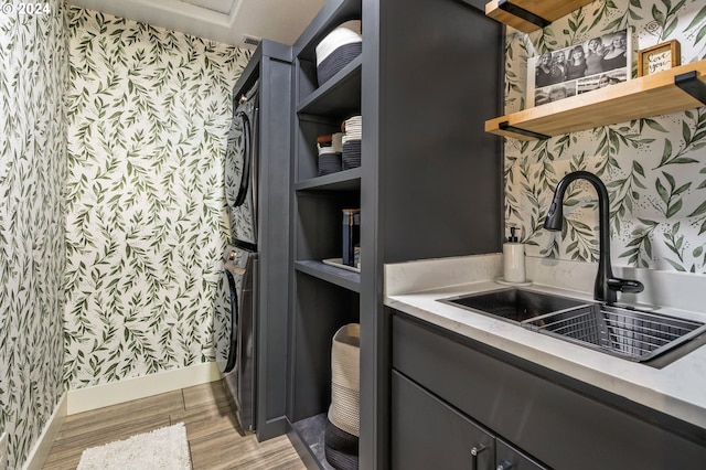 interior space featuring sink, stacked washer / drying machine, and light hardwood / wood-style flooring