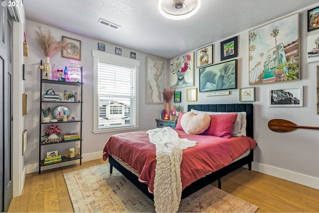 bedroom featuring a textured ceiling and light hardwood / wood-style flooring