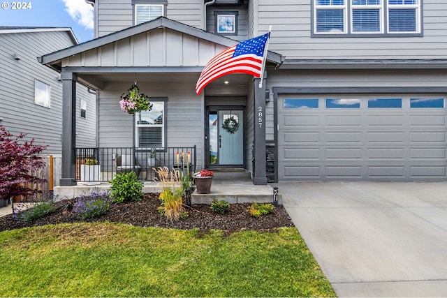 view of exterior entry featuring a lawn, a porch, and a garage