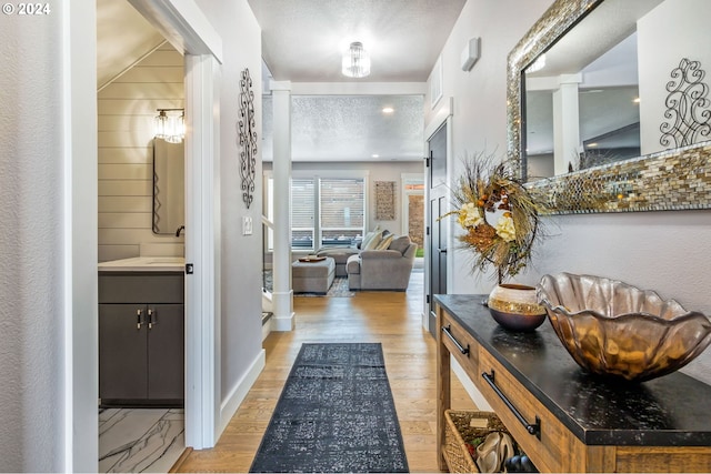 corridor featuring a textured ceiling and light hardwood / wood-style floors