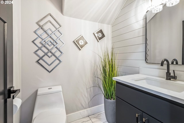 bathroom featuring vanity, wood walls, and toilet