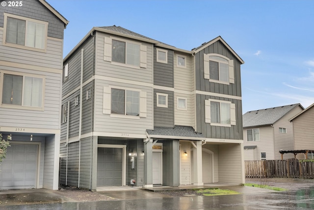 multi unit property with a garage, a shingled roof, fence, and board and batten siding