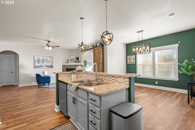 kitchen with a sink, arched walkways, light wood-style floors, and a fireplace