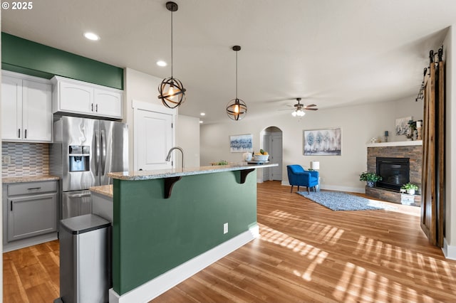 kitchen featuring backsplash, light wood-style floors, a fireplace, and stainless steel refrigerator with ice dispenser