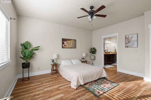 bedroom featuring ensuite bath, wood finished floors, and baseboards