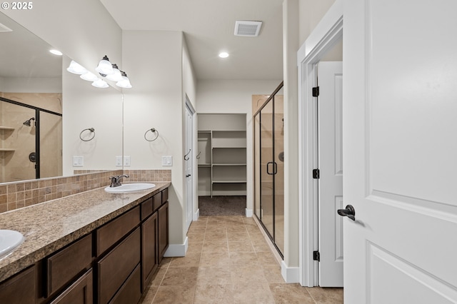 bathroom featuring tasteful backsplash, visible vents, a stall shower, and a sink