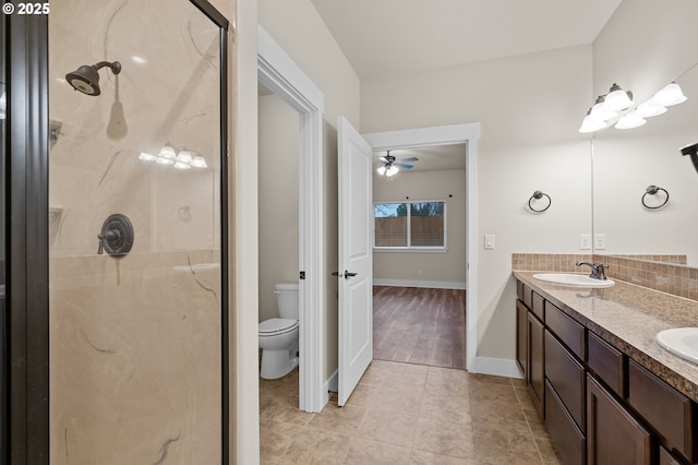 full bath with baseboards, double vanity, a stall shower, a sink, and toilet