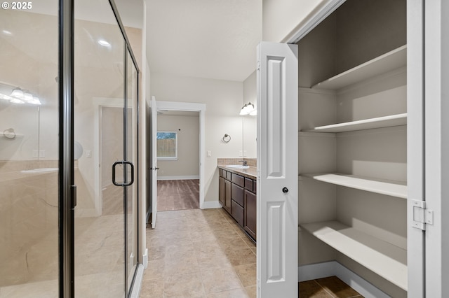 full bathroom featuring double vanity, a stall shower, and a sink