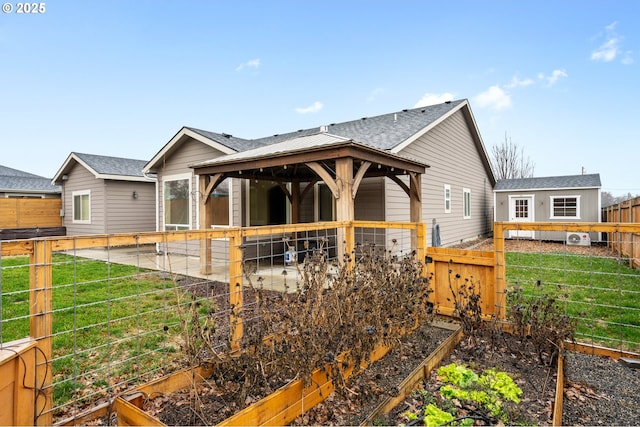 back of house with a gazebo, a vegetable garden, a fenced backyard, and a patio