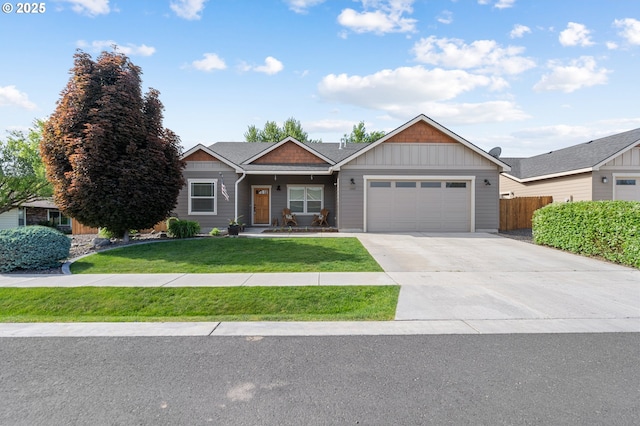 view of front facade featuring driveway, fence, board and batten siding, an attached garage, and a front yard