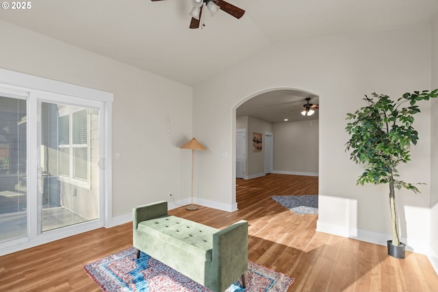 sitting room featuring vaulted ceiling, wood finished floors, arched walkways, and baseboards