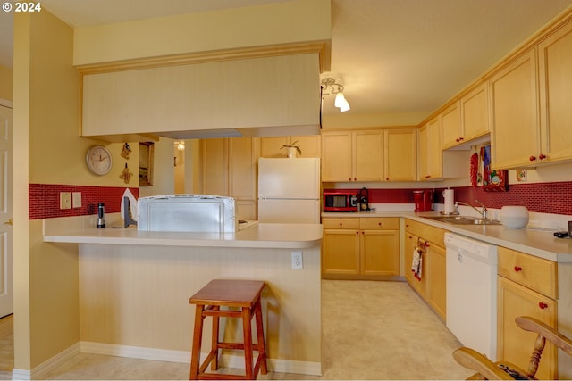 kitchen featuring kitchen peninsula, light brown cabinets, white appliances, and sink