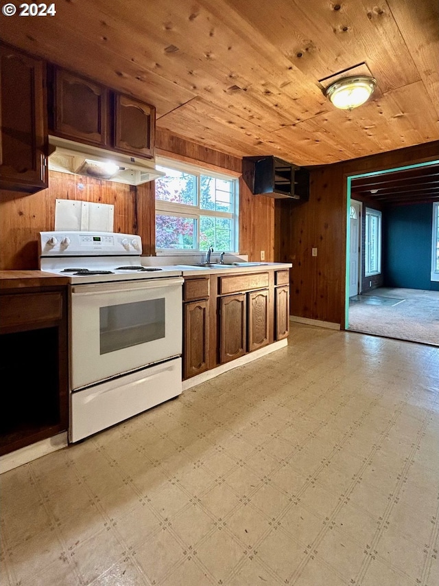 kitchen with wood ceiling, wood walls, white electric stove, and sink