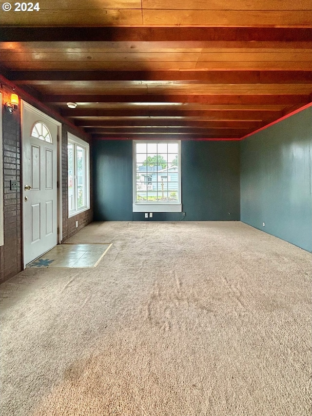 carpeted empty room featuring beam ceiling