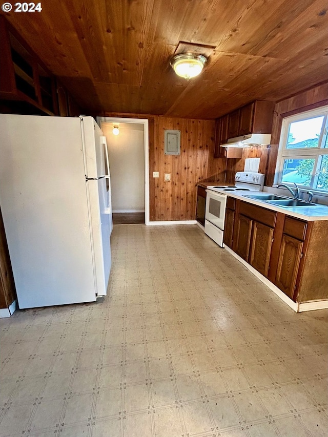 kitchen with white appliances, wooden ceiling, sink, and wooden walls