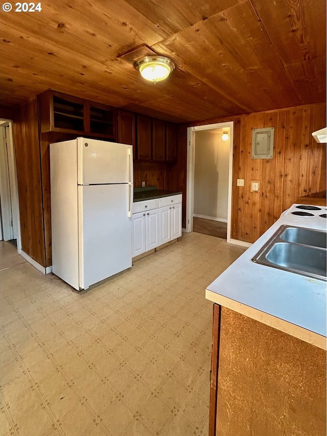 kitchen featuring a sink, freestanding refrigerator, light floors, wood walls, and wood ceiling