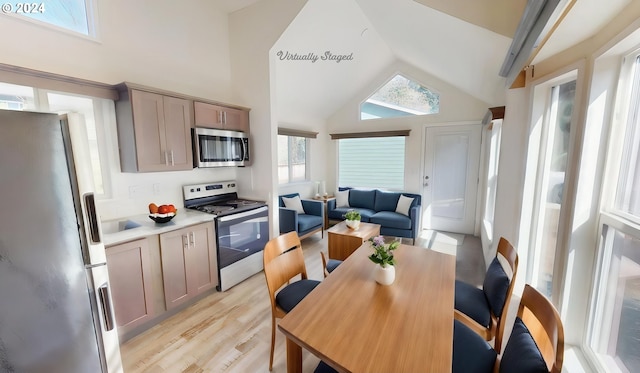 kitchen with light hardwood / wood-style floors, appliances with stainless steel finishes, and vaulted ceiling