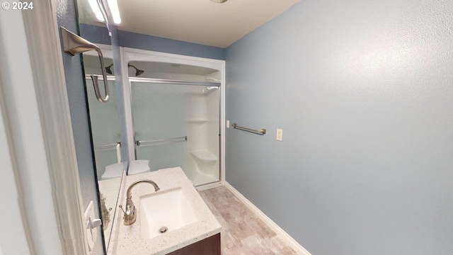 bathroom with hardwood / wood-style flooring, an enclosed shower, and vanity