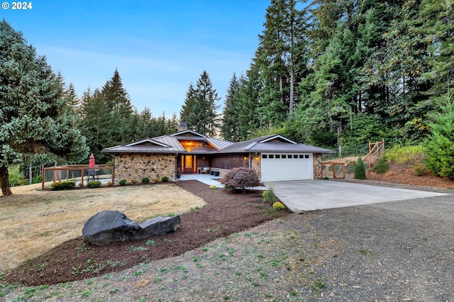 view of front of home with driveway, a standing seam roof, a garage, stone siding, and metal roof